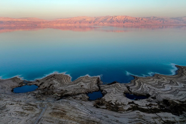 -Près du kibboutz israélien Ein Gedi, des gouffres remplis d'eau se sont formés à la suite d'une baisse du niveau d'eau dans la mer Morte le 21 septembre 2021. L'eau bleue recule d'environ un mètre chaque année, laissant derrière elle un paysage lunaire blanchi au sel et perforé de trous béants. Photo de Menahem KAHANA / AFP via Getty Images.