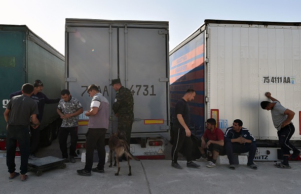 Les agents des douanes vérifient la cargaison de pommes de terre en provenance d'Afghanistan, le 18 octobre 2021. Les chauffeurs accroupis partagent des plaintes sur la façon dont le commerce a souffert depuis que les talibans ont pris le pouvoir. Photo de VYACHESLAV OSELEDKO/AFP via Getty Images.