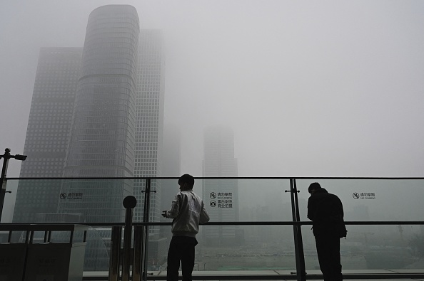 Deux hommes à côté d'un mur de verre sur un balcon par une journée polluée à Pékin le 5 novembre 2021. Photo de JADE GAO / AFP via Getty Images.