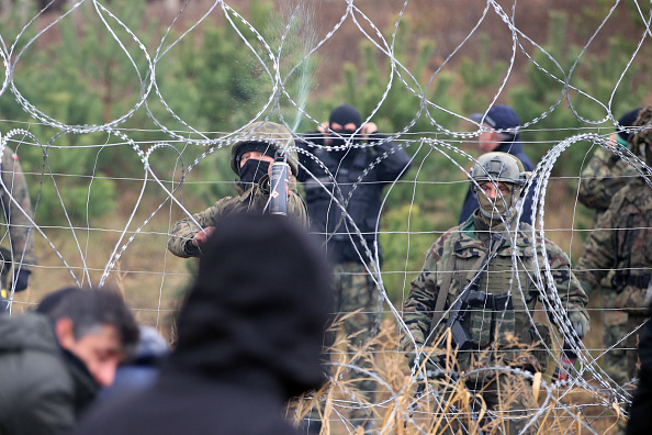 Le 8 novembre 2021  des agents des forces de l'ordre polonaises bloquent des migrants à la frontière biélorusse-polonaise.(Photo : LEONID SHCHEGLOV/BELTA/AFP via Getty Images)