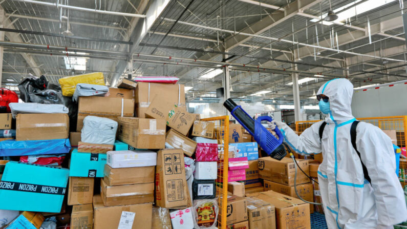 Employé pulvérisant du désinfectant sur des paquets à livrer pour prévenir le coronavirus dans une entreprise de logistique à Zhangye, dans la province chinoise du Gansu (nord-ouest), le 16 novembre 2021 (Photo par STR/AFP via Getty Images)