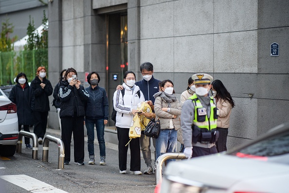 Les élèves arrivent avec des membres de leur famille, avant de passer les examens annuels d'entrée à l'université, connus localement sous le nom de "suneung" à Séoul le 18 novembre 2021. Photo par Anthony WALLACE / AFP via Getty Images.