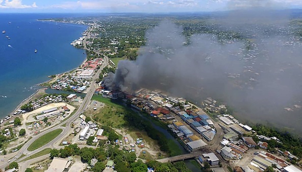 -La fumée des bâtiments en flammes s'élève de Honiara dans les Îles Salomon le 25 novembre 2021. Photo de Robert TAUPONGI / AFP via Getty Images.
