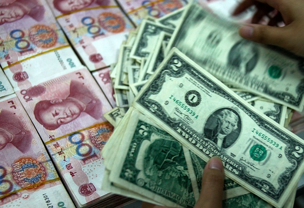 Des dollars américains et des yuans chinois dans une banque de Huaibei. Photo par STR/AFP via Getty Images.
