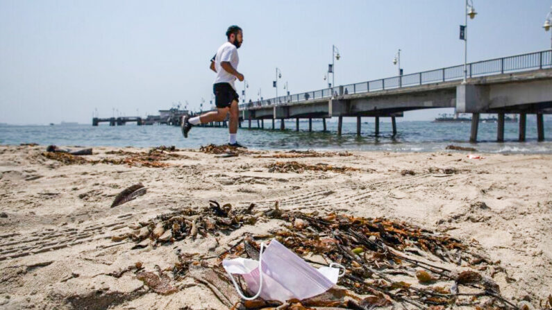 Un homme court à côté d'un masque facial jeté à Long Beach, en Californie, le 22 août 2020. (Apu Gomes/AFP via Getty Images)