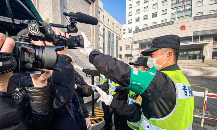 Un policier couvre une caméra pour empêcher les journalistes d'enregistrer des images devant le tribunal populaire du nouveau district de Shanghai Pudong, où la journaliste citoyenne chinoise Zhang Zhan doit être jugée à Shanghai, le 28 décembre 2020. (Leo Ramirez/AFP via Getty Images)