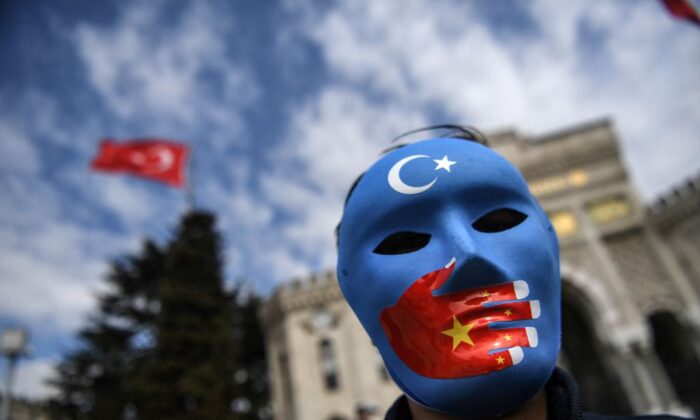 Un manifestant portant un masque peint aux couleurs du drapeau du Turkestan oriental prend part à une manifestation de partisans de la minorité ouïgoure, le 1er avril 2021, sur la place Beyazid à Istanbul. (Ozan Kose/AFP via Getty Images)