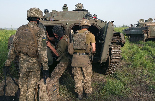 -Des militaires ukrainiens se rassemblent près d'un véhicule blindé de transport de troupes stationné le long de la ligne, dans la région de Donetsk, le 23 juin 2021. Photo d'Anatolii STEPANOV / AFP via Getty Images.