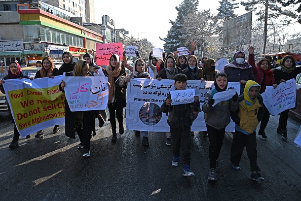 -Des femmes scandent des slogans et brandissent des pancartes lors d'une manifestation exigeant l'égalité des droits, le long d'une route à Kaboul le 16 décembre 2021. Photo de WAKIL KOHSAR/AFP via Getty Images.