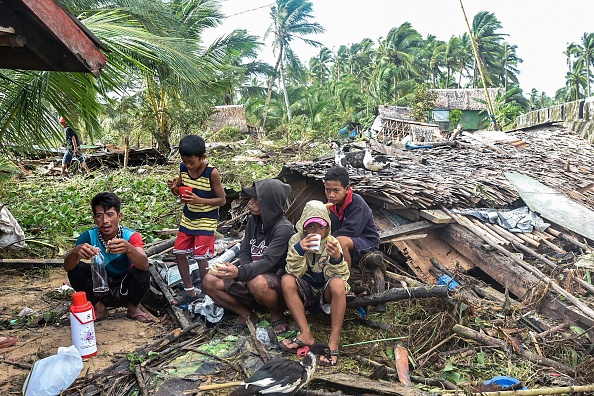 -Des habitants se rassemblent près d'une maison effondrée dans la ville de Hernani, le 17 décembre 2021, un jour après que le super typhon Rai a frappé les régions du sud et du centre des Philippines. Photo par Alren BERONIO / AFP via Getty Images.