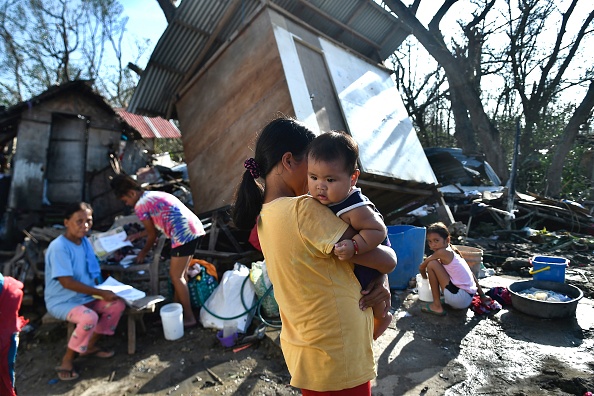 -Des habitants se rassemblent à côté de leur maison détruite à Carcar, le 18 décembre 2021, quelques jours après que le super typhon Rai a frappé la ville. Photo de Victor KINTANAR / AFP via Getty Images.
