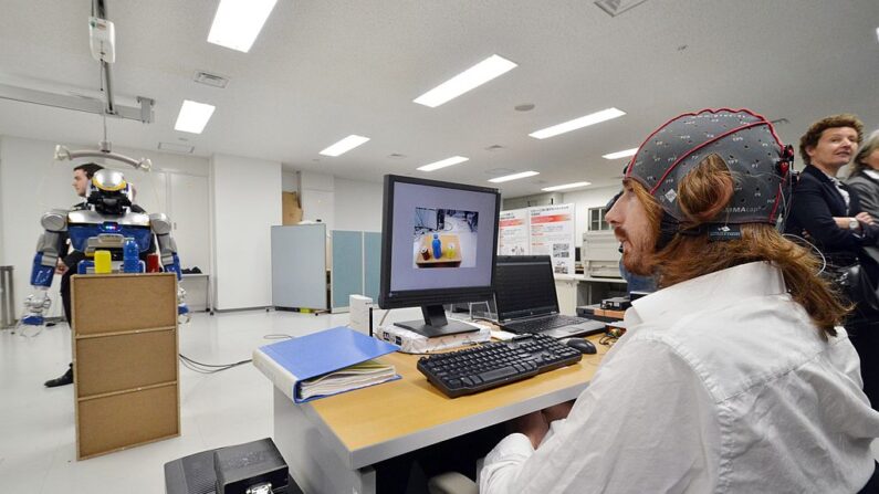 Des chercheurs français présentent un robot humanoïde HRP-2, qui est contrôlé par l'activité cérébrale humaine avec l'interface cerveau-machine (ICM) dans le laboratoire commun Japon-France à l'Institut national des sciences et technologies industrielles avancées (AIST) à Tsukuba, dans la banlieue de Tokyo, le 29 mars 2013.  (YOSHIKAZU TSUNO/AFP via Getty Images)