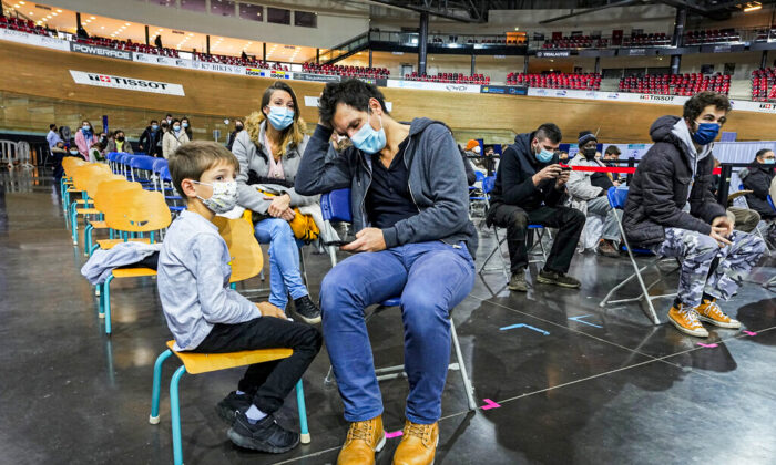 Hugo Chappaz, 9 ans, à gauche, attend avec son père Benoit Chappaz, à droite, et sa mère pour être vacciné au Vélodrome national de Saint-Quentin-en-Yvelines, à l'ouest de Paris, en France, le 22 décembre 2021. (Michel Euler/ AP Photo)