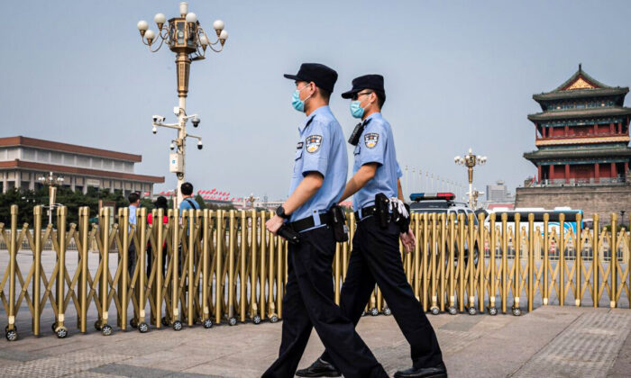 Des policiers patrouillent dans une zone à l'extérieur de la place Tiananmen de Pékin (de dos) lors de la Journée mondiale de la liberté de la presse, le 3 mai 2020. (Photo par NICOLAS ASFOURI / AFP) (Photo par NICOLAS ASFOURI/AFP via Getty Images)