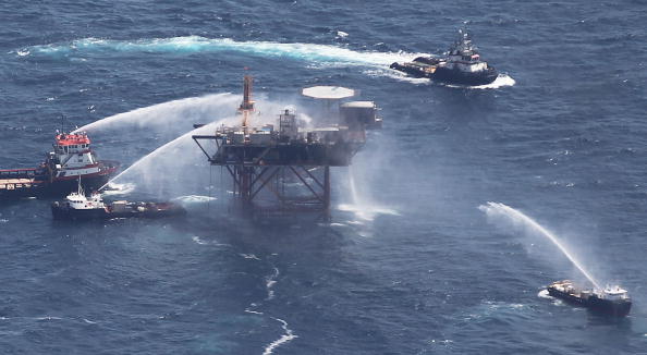 -Illustration- Des bateaux pulvérisent de l'eau sur une plate-forme pétrolière après son explosion dans le golfe du Mexique au large de la Louisiane. Photo de Mario Tama/Getty Images.