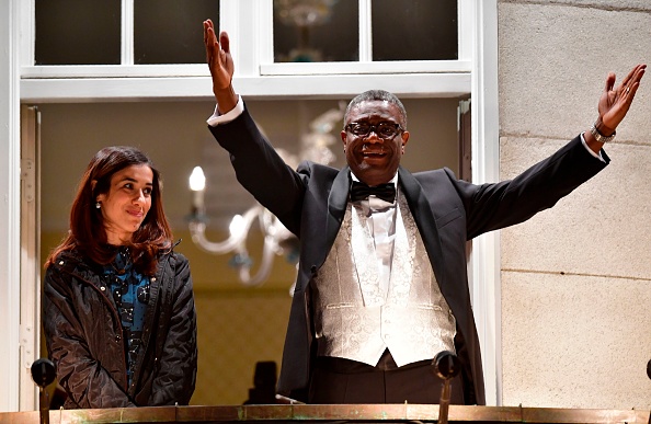 Les lauréats du prix Nobel, le gynécologue congolais Denis Mukwege et la militante des droits humains yézidie-kurde irakienne Nadia Murad saluent la foule depuis le balcon de la suite du Nobel dans le centre-ville d'Oslo, en Norvège, le 10 décembre 2018. Photo de Tobias SCHWARZ / AFP via Getty Images.