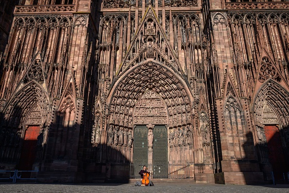Le musicien de rue Brice Bauer joue du violoncelle sur la place vide de la cathédrale dans le centre de Strasbourg, dans l'est de la France, le 22 mars 2020 (PATRICK HERTZOG/AFP via Getty Images)