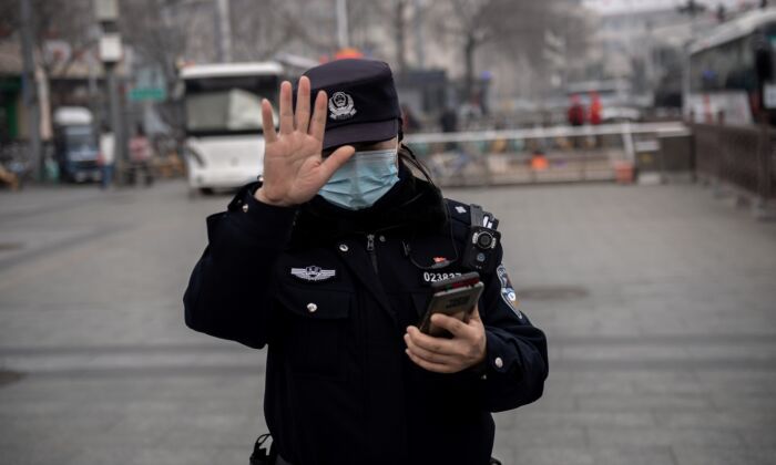 Un officier de police fait signe à un journaliste de ne pas photographier à Pékin, en Chine, le 5 mars 2021. (NICOLAS ASFOURI/AFP via Getty Images)