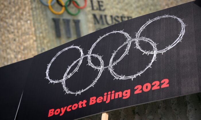 Une pancarte avec du fil barbelé en forme d'anneaux olympiques est placée à côté d'un panneau du Musée des Jeux olympiques lors d'une manifestation organisée par des militants tibétains et ouïghours contre les Jeux olympiques d'hiver de Pékin 2022, à Lausanne, en Suisse, le 23 juin 2021. (Fabrice Coffrini/AFP via Getty Images)