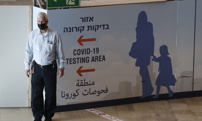 Un membre du personnel aide les passagers qui arrivent à l'aéroport Ben Gourion d'Israël à Lod, à l'est de Tel Aviv, le 28 novembre 2021. (Ahmad Gharabli/AFP via Getty Images)