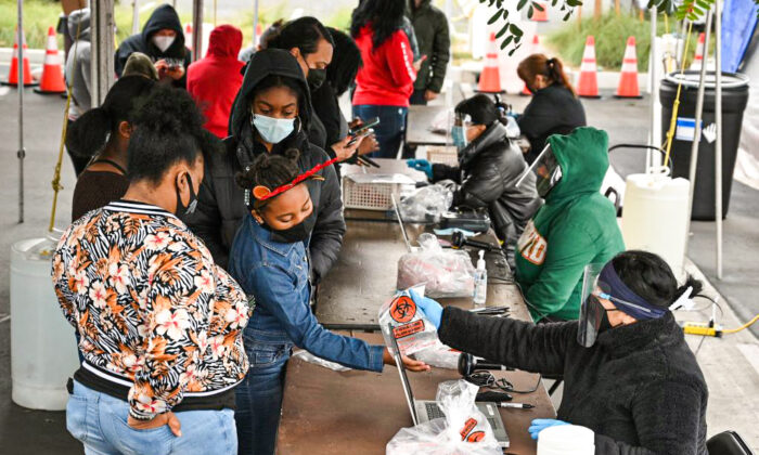 Une jeune fille reçoit un kit de test Covid-19 à faire soi-même dans un centre de dépistage du Martin Luther King, Jr. Medical Center Campus à South Los Angeles, en Californie, le 27 décembre 2021. (Robyn Beck/AFP via Getty Images)