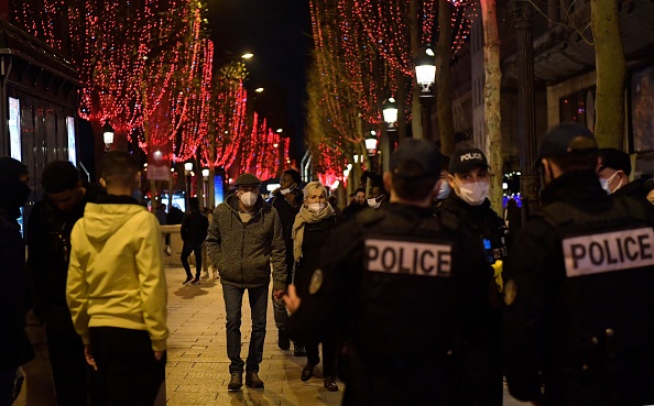 Sur l'avenue des Champs-Élysées des policiers patrouillent pour vérifier le respect du port obligatoire de masques faciaux pour éviter la propagation du Covid-19, à Paris, le 31 décembre 2021. (JULIEN DE ROSA/AFP via Getty Images)