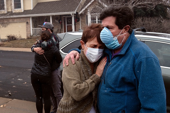 Louie Delaware embrasse sa femme Judy alors que sa fille Elise embrasse son fiancé McGregor Ritter après son retour dans les restes de leur maison à Louisville, Colorado, le 31 décembre 2021. Photo de Jason Connolly / AFP via Getty Images.