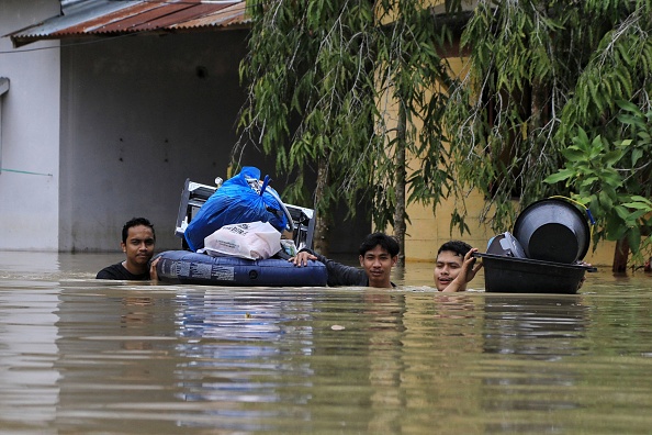 -Les résidents transportent leurs effets personnels alors qu'ils évacuent leurs maisons inondées, Aceh, le 2 janvier 2022. Photo par Azwar Ipank / AFP via Getty Images.