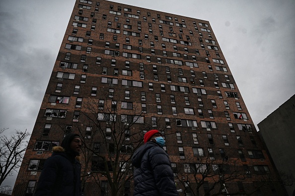 Des personnes se tiennent devant un immeuble d'habitation après un incendie dans le Bronx, le 9 janvier 2022, à New York.  (Photo : ED JONES/AFP via Getty Images)