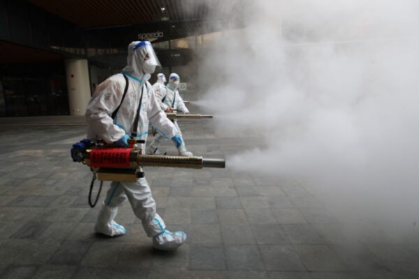 Des membres du personnel portant des équipements de protection individuelle pulvérisent du désinfectant à l'extérieur d'un centre commercial à Xi'an, en Chine, le 11 janvier 2022. (STR/AFP via Getty Images)