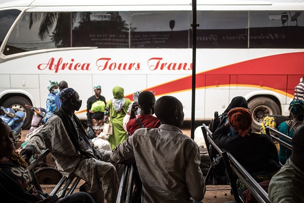 -Des voyageurs sont assis sur des bancs dans une gare routière en attendant la reprise des transports transfrontaliers à Bamako le 11 janvier 2022. Le trafic est perturbé entre le Mali et les pays voisins. Photo de FLORENT VERGNES / AFP via Getty Images.