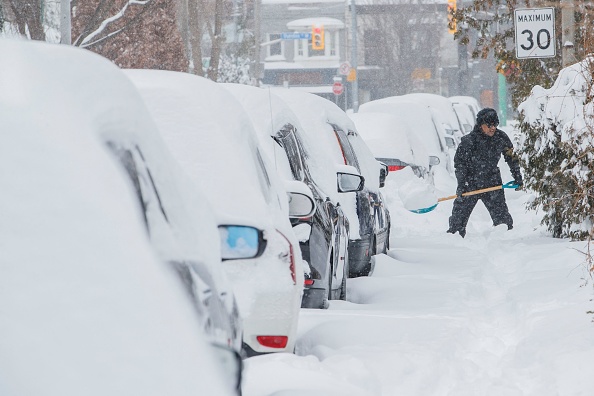 Une personne sort sa voiture de sous la neige à Toronto, Ontario, Canada, le 17 janvier 2022. Photo de Cole BURSTON/AFP via Getty Images.