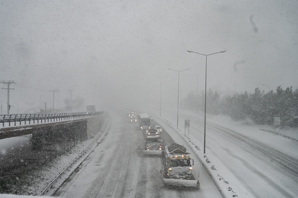 -Les pistes de la protection civile grecque nettoient la neige de la route nationale menant à la ville d'Athènes le 24 janvier 2022. Photo par Aris MESSINIS/AFP via Getty Images.