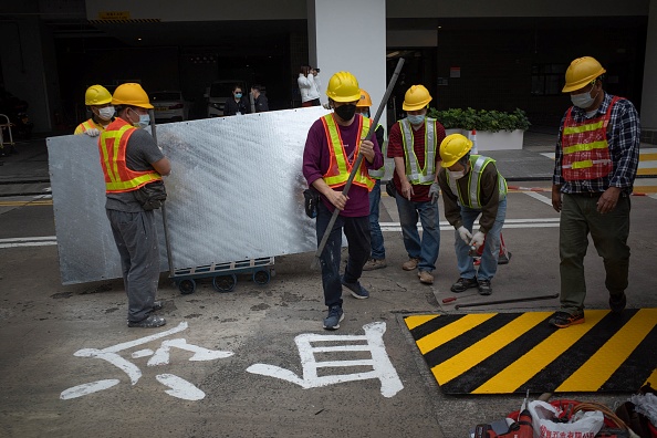 -Des ouvriers recouvrent des caractères chinois, l'un des derniers hommages publics à la répression meurtrière de la place Tiananmen en 1989, sur une passerelle du campus de l'Université de Hong Kong, le 29 janvier 2022. Photo de Bertha WANG / AFP via Getty Images.