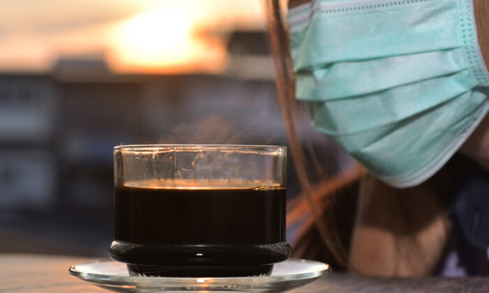 Cup of fragrant black coffee with woman wearing the sugical mask trying to check the anosmia in covid-19