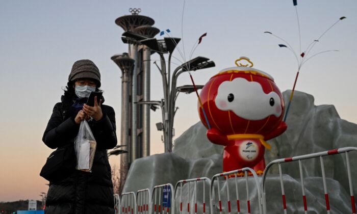 Une femme regarde son téléphone devant une installation de Shuey Rhon Rhon, mascotte des Jeux paralympiques d'hiver de Pékin 2022, au parc olympique de Pékin, le 13 janvier 2022. (Jade Gao/AFP via Getty Images)