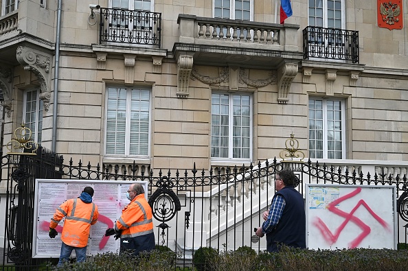 Des employés nettoient des tags de croix gammées sur la clôture du consulat russe à Strasbourg, le 25 février 2022. (Photo : PATRICK HERTZOG/AFP via Getty Images)