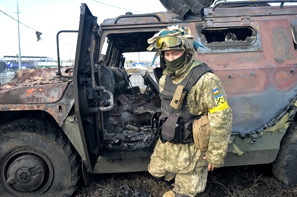 -Un combattant de la Défense territoriale ukrainienne examine un véhicule de mobilité d'infanterie russe GAZ détruit après le combat à Kharkiv le 27 février 2022. Photo de SERGEY BOBOK/AFP via Getty Images.