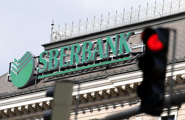 -Le logo de la banque publique russe Sberbank est représenté à côté d'un feu rouge, au siège de sa filiale européenne à Vienne le 28 février 2022. Photo de ROLAND SCHLAGER/APA/AFP via Getty Images.