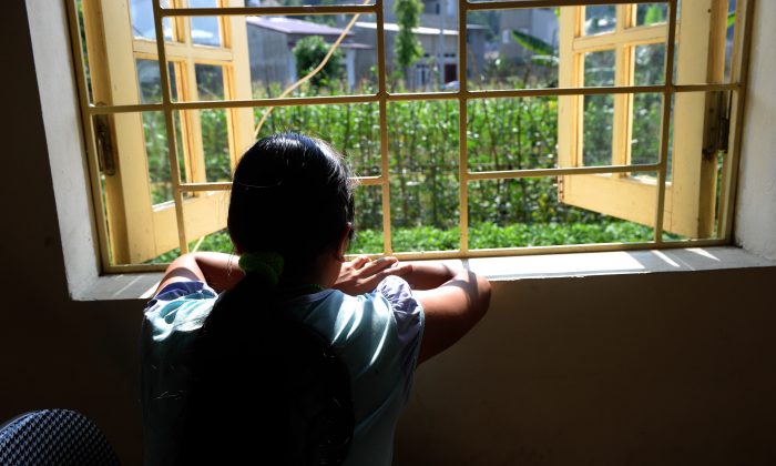  Kiab, une jeune fille de l'ethnie h'mong,(pseudonyme pour protéger son identité), regarde par la fenêtre d'un centre pour femmes victimes de la traite des êtres humains dans la ville de Lao Cai, au nord du pays, le 9 mai 2014. Lorsque Kiab a eu 16 ans, son frère a promis de l'emmener à une fête dans une ville touristique du nord du Vietnam. Au lieu de cela, il l'a vendue à une famille chinoise comme épouse. (Hoang Dinh Nam/AFP/Getty Images)