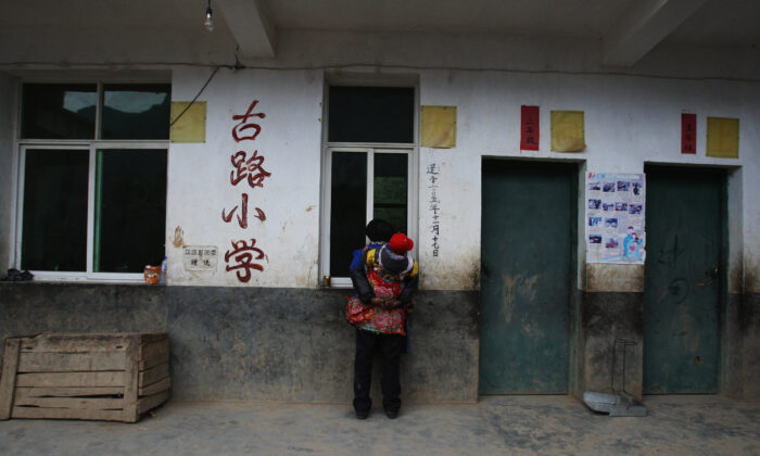 Une femme âgée de l'ethnie Yi observe des élèves qui participent à une leçon à l'école du village de Gulucan, le 17 novembre 2008, dans le comté de Hanyuan, province du Sichuan, en Chine. (Guang Niu/Getty Images)