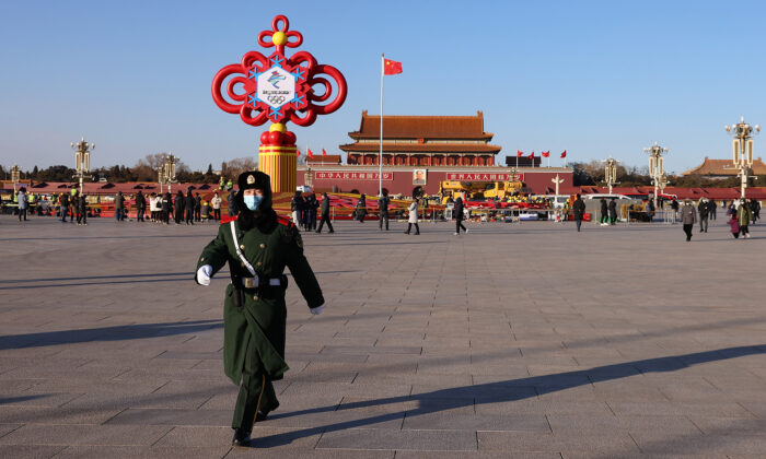 Un policier armé défile devant le monument de 17 mètres de haut entouré d'un parterre de fleurs érigé à l'occasion des JO sur le thème des "Merveilleux Jeux olympiques d'hiver" sur la place Tiananmen, le 15 janvier 2022 à Pékin, en Chine. (Lintao Zhang/Getty Images)