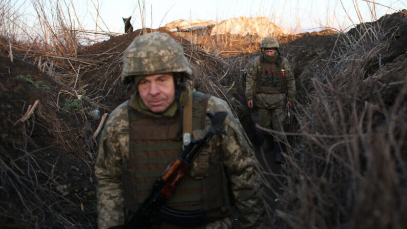 Les forces militaires ukrainiennes marchent le long des tranchées qui se trouvent sur la ligne de front face aux séparatistes soutenus par la Russie, près du village de Novognativka, dans la région de Donetsk en Ukraine, le 21 février 2022. (AnatoliI Stepanov/AFP via Getty Images)