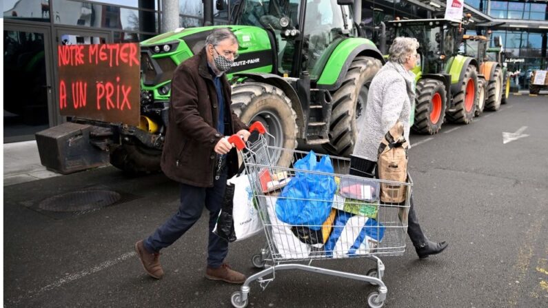 Des clients passent devant les tracteurs des membres du syndicat d'agriculteurs FDSEA 35 alors qu'ils mènent une opération visant à contrôler les prix et l'origine des produits dans un supermarché de Rennes, dans l'ouest de la France, le 4 février 2022. (Photo par DAMIEN MEYER/AFP via Getty Images)