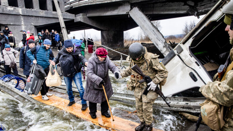 Les habitants d'Irpin, en Ukraine, fuient les combats violents en empruntant un pont détruit alors que les forces russes pénètrent dans la ville, le 7 mars 2022. (Chris McGrath/Getty Images)