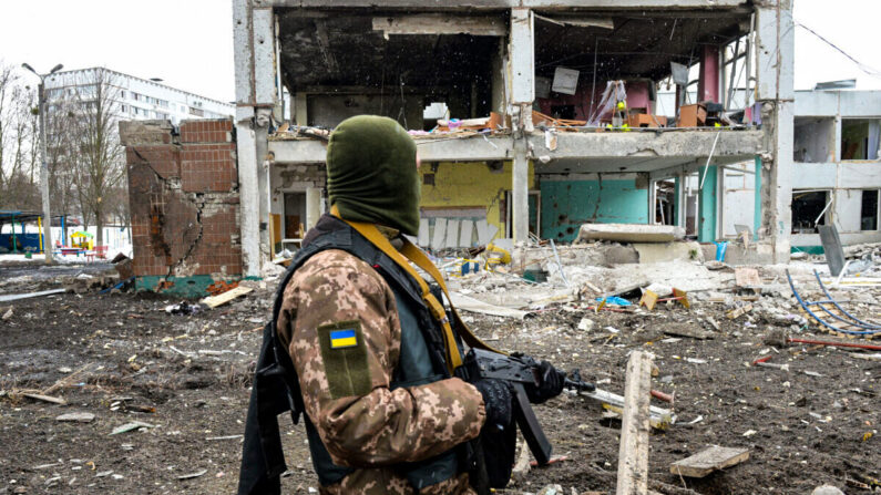Un membre des forces de défense territoriale ukrainiennes regarde les dégâts causés par un bombardement dans la deuxième ville d'Ukraine, Kharkiv, le 8 mars 2022. (Sergey Bobok/AFP via Getty Images)
