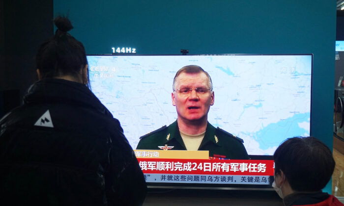 Des habitants regardent un écran de télévision montrant des informations sur le conflit entre la Russie et l'Ukraine dans un centre commercial à Hangzhou, dans la province chinoise du Zhejiang (est), le 25 février 2022. (STR/AFP via Getty Images)