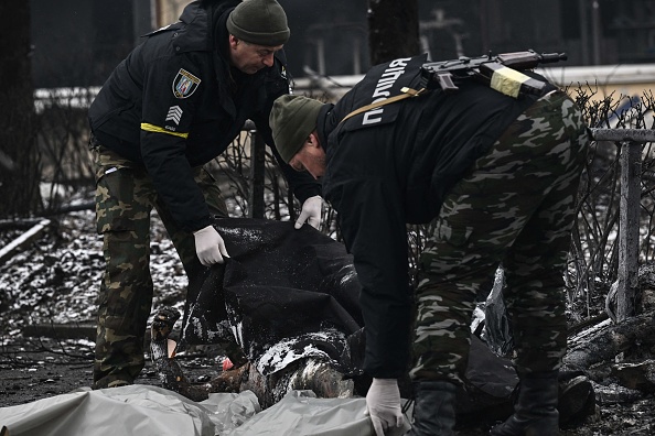 Des policiers couvrent les corps des passants tués lors de la frappe aérienne d'hier qui a frappé la tour de télévision principale de Kiev à Kiev le 2 mars 2022. Photo par Aris MESSINIS/AFP via Getty Images.