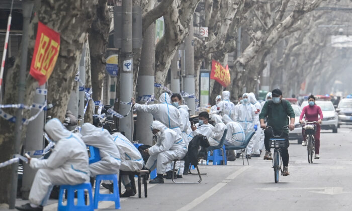 Des ouvriers portent des vêtements de protection près de certaines zones de confinement après la détection de nouveaux cas de Covid-19 à Shanghai, le 14 mars 2022. (Hector Retamal/AFP via Getty Images)
