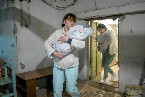 -Des infirmières transportent des bébés au sous-sol de la maternité alors que les sirènes avertissent des raids aériens à Mykolaïv, le 14 mars 2022. Photo de BULENT KILIC / AFP via Getty Images.